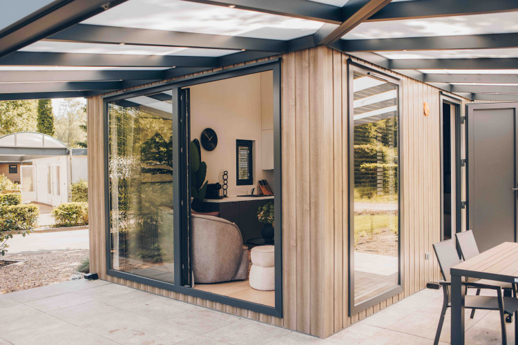 Moderne lodge met grote ramen, houten gevelbekleding en buitenterras, omgeven door groen.