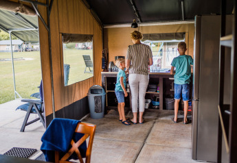 Una famiglia si trova nella cucina di una tenda safari, con due bambini e un adulto visti da dietro.