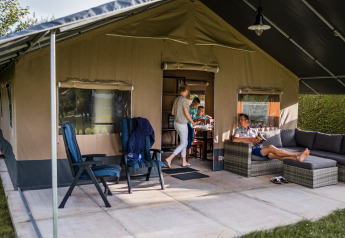 Famiglia si rilassa e trascorre del tempo insieme davanti a una tenda safari di lusso con divani.
