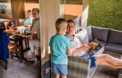 Una familia pasa tiempo junta en una tienda safari con mesa de comedor y zona de descanso, rodeada de vegetación.