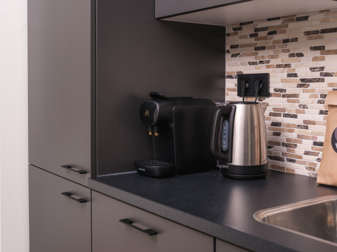 Küchenzeile mit Espressomaschine, Wasserkocher und Mosaikfliesenwand in einer modernen Lodge-Küche.