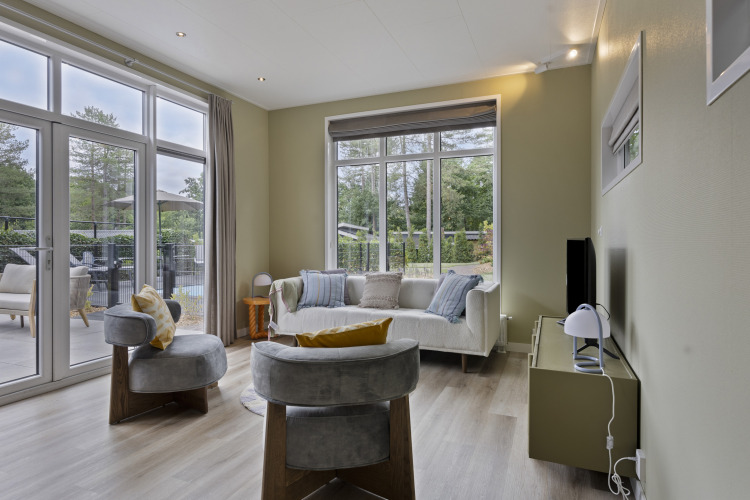 Modernes Wohnzimmer einer 10-Personen-Lodge mit großen Fenstern und gemütlicher Einrichtung bei De Thijmse Berg.