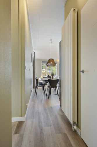 Ein schmaler Flur mit Holzboden führt zu einem Essbereich in einer modernen Lodge in De Thijmse Berg, Niederlande.