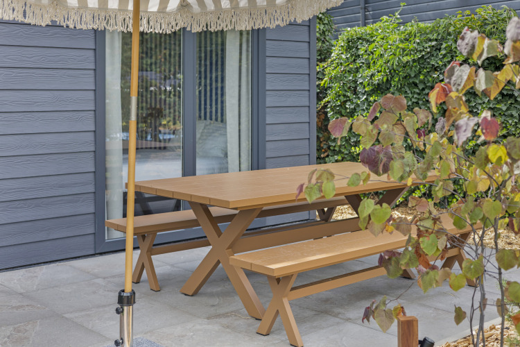 Holzpicknicktisch und Bänke im Freien vor einer Lodge an der Thijmse Berg in den Niederlanden, umgeben von Pflanzen.