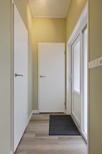 Eingangsbereich mit weißen Türen und Holzboden in einer 10-Personen-Lodge auf De Thijmse Berg, Niederlande.