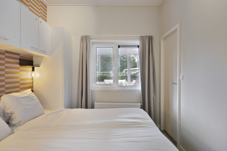 Modernes Schlafzimmer mit Doppelbett, weißen Schränken und Fenster in einer Lodge auf De Thijmse Berg.