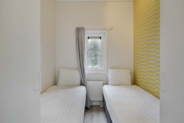 Zwei Einzelbetten mit weißen Bettbezügen in einem kompakten Gästezimmer der De Thijmse Berg-Lodge.