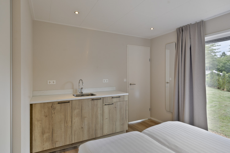 Modernes Lodge-Zimmer im De Thijmse Berg mit Spüle, Spiegel, großem Fenster und Blick ins Grüne.