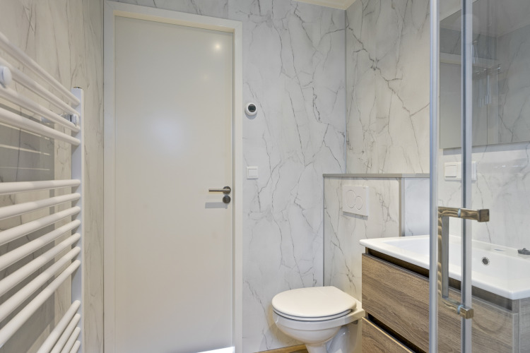 Modernes Badezimmer mit weißen Marmorböden und -wänden, Toilette, Waschbecken und Dusche in einer Lodge.