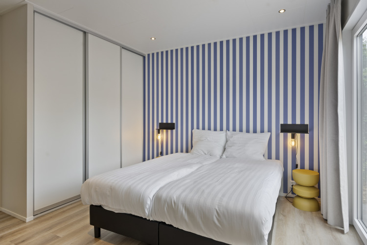 Modernes Schlafzimmer in einer Lodge mit blauen und weißen Streifen, Doppelbett und Schrank in De Thijmse Berg, Niederlande.