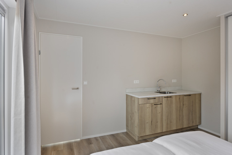 Modernes Lodge-Interieur mit Küchenzeile, Spüle, hellen Wänden und Holzboden bei De Thijmse Berg, Niederlande.