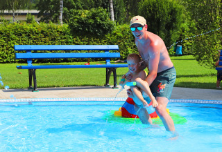 A man and child play together in a pool at Campingpark Echternacherbrück, Rhineland-Palatinate, Germany.