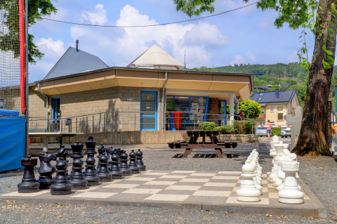 Juego de ajedrez gigante al aire libre frente a un edificio moderno en Campingpark Echternacherbrück, Renania-Palatinado.