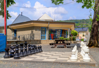 Outdoor giant chess set in front of a modern building at Campingpark Echternacherbrück, Rhineland-Palatinate.