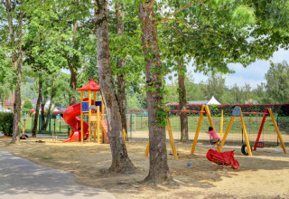Parco giochi con altalene, scivolo e alberi al Campingpark Echternacherbrück in Renania-Palatinato, Germania.