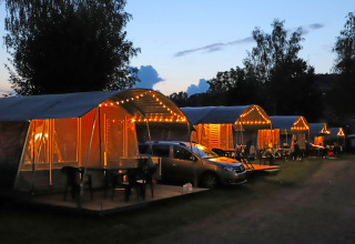 Illuminated camping tents and cars at dusk at Campingpark Echternacherbrück, Rhineland-Palatinate, Germany.