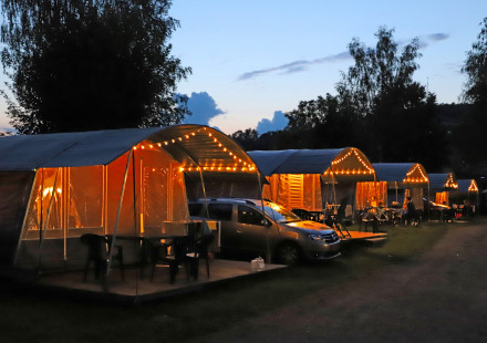 Verlichte campingtenten en auto’s bij schemering op Campingpark Echternacherbrück, Rijnland-Palts, Duitsland.