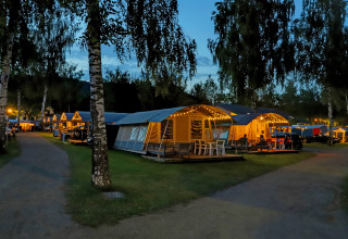 Vista nocturna del Campingpark Echternacherbrück en Alemania con cabañas iluminadas y ambiente acogedor.