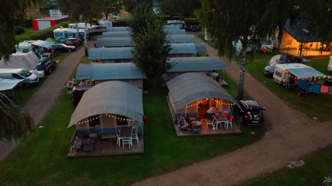 Aerial view of cozy cabins with covered terraces and string lights at Campingpark Echternacherbrück, Germany.