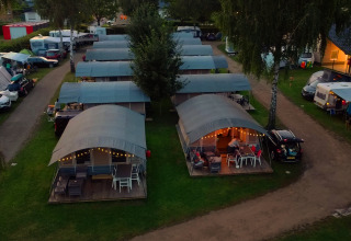 Aerial view of cozy cabins with covered terraces and string lights at Campingpark Echternacherbrück, Germany.