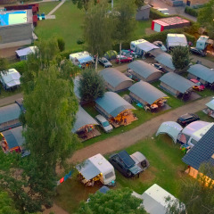 Vista aerea del Campingpark Echternacherbrück in Germania con roulotte, tende e piscina illuminata di sera.