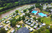 Aerial view of Campingpark Echternacherbrück in Germany with tents, caravans, pools, and a river.