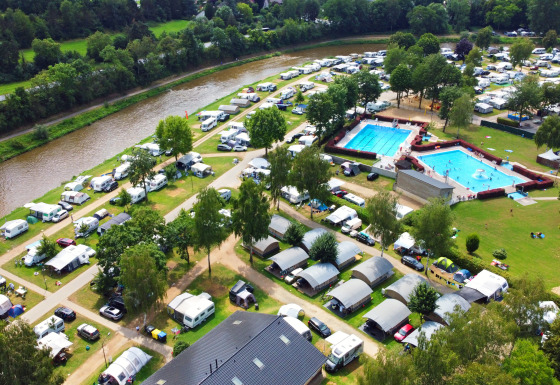 Vista aérea de Campingpark Echternacherbrück, Alemania, con tiendas, caravanas, piscinas y un río.
