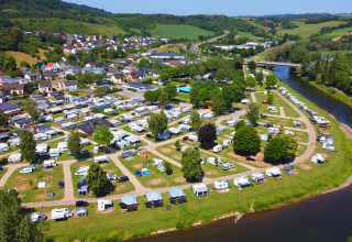 Luchtfoto van de camping in Echternacherbrück, Duitsland, met campers langs een rivier en veel groen.