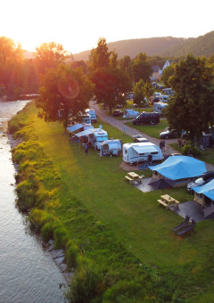 Campingpark Echternacherbrück in Rheinland-Pfalz, Deutschland, mit Zelten und Wohnwagen am Fluss.