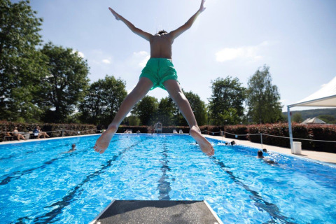 Enfant sautant du plongeoir dans la piscine du Campingpark Echternacherbrück, Rhénanie-Palatinat, Allemagne.