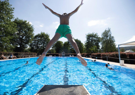 Kind springt van de duikplank in het zwembad op Campingpark Echternacherbrück, Rijnland-Palts, Duitsland.