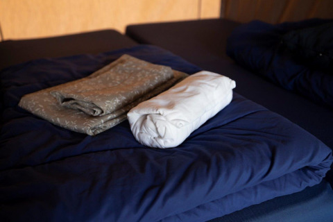 Folded and rolled bedding on a blue bed at Campingpark Echternacherbrück in Rhineland-Palatinate, Germany.