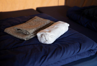 Gefaltete und gerollte Bettwäsche auf einem blauen Bett im Campingpark Echternacherbrück, Rheinland-Pfalz.