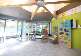 Lyst og moderne receptionsområde på Campingpark Echternacherbrück med Rent a Bike-banner og glasdøre.
