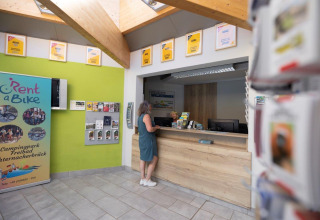 Reception area at Campingpark Echternacherbrück in Germany, featuring a guest, a counter, and brochures.