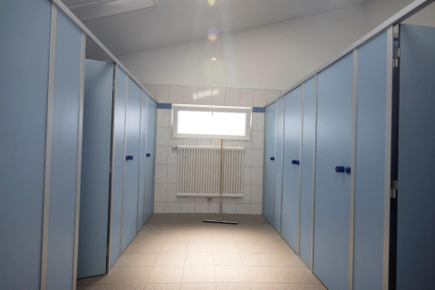 Clean, modern restroom stalls with blue doors in the sanitary building at Campingpark Echternacherbrück, Germany.