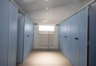 Clean, modern restroom stalls with blue doors in the sanitary building at Campingpark Echternacherbrück, Germany.
