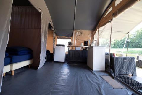 Vista interna di una tenda glamping con letti, angolo cottura e salottino al Campingpark Echternacherbrück.