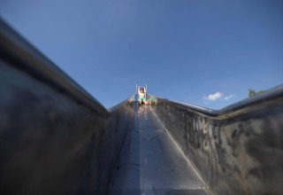 Child seen from the bottom of a slide under a blue sky at Campingpark Echternacherbrück, Germany.