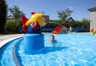 Bambini che giocano in piscina con scivolo e decorazioni colorate al Campingpark Echternacherbrück, Germania.