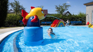 Kinder spielen im Schwimmbad mit Rutsche und bunten Figuren im Campingpark Echternacherbrück, Rheinland-Pfalz.