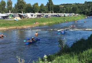 Holidaymakers kayak and swim in the river at Campingpark Echternacherbrück in Rhineland-Palatinate, Germany.