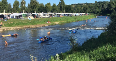 Holidaymakers kayak and swim in the river at Campingpark Echternacherbrück in Rhineland-Palatinate, Germany.