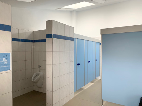 Bright, clean restroom at Campingpark Echternacherbrück with blue stall doors and a single urinal.