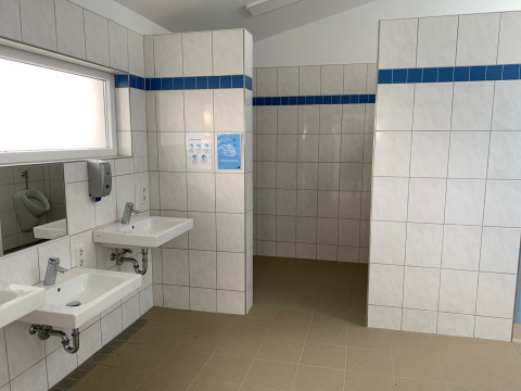 Bagno moderno al Campingpark Echternacherbrück con piastrelle bianche e lavandini in Renania-Palatinato, Germania.