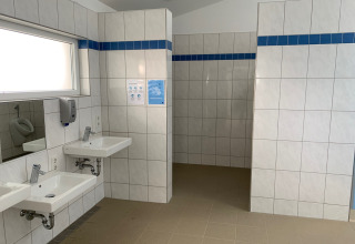 Bagno moderno al Campingpark Echternacherbrück con piastrelle bianche e lavandini in Renania-Palatinato, Germania.