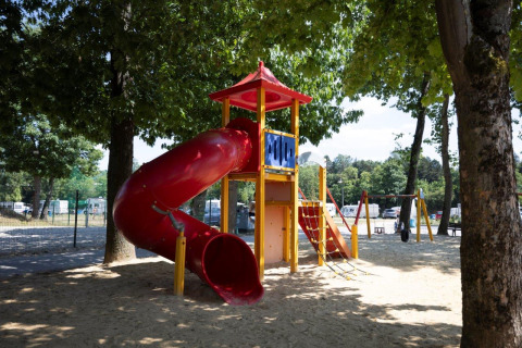 Parco giochi con scivolo rosso e struttura da arrampicata tra gli alberi a Campingpark Echternacherbrück, Germania.