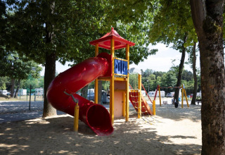 Parco giochi con scivolo rosso e struttura da arrampicata tra gli alberi a Campingpark Echternacherbrück, Germania.