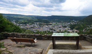 Zicht op Echternacherbrück vanaf een heuvel met bankje, infobord en groene heuvels op de achtergrond.