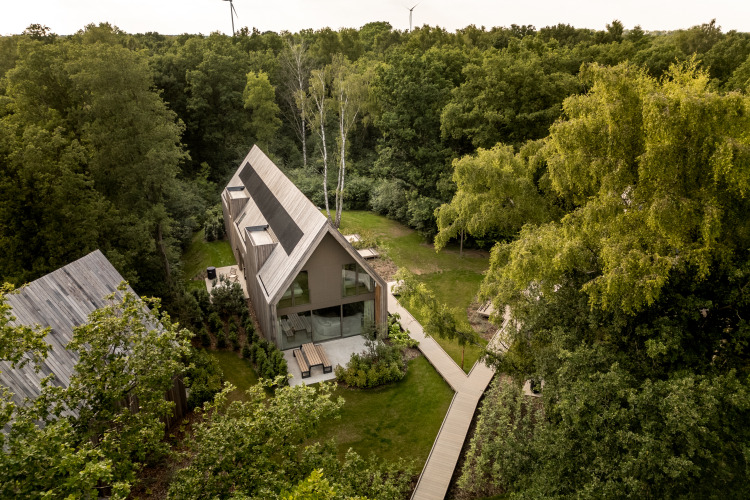 Vista aérea de Lodge at Woodz Lodges en Bélgica, rodeado de bosque denso y arquitectura moderna.
